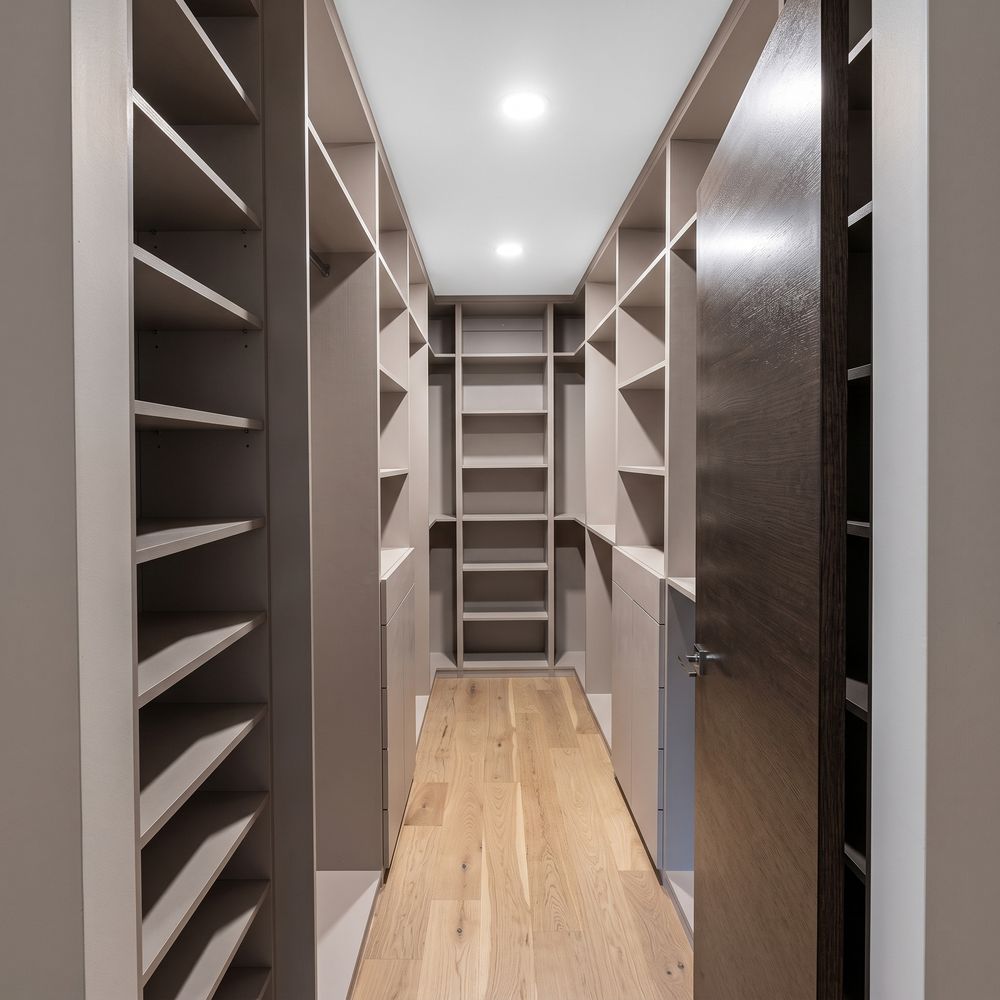 Vestidor tipo pasillo en acabado taupe con estantería a ambos lados y puerta de madera