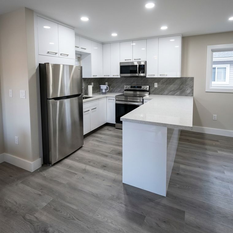 Cocina blanca con península, nevera de acero inoxidable y piso gris