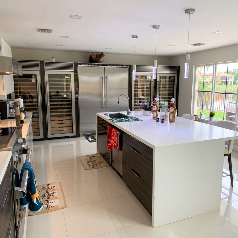 Cocina amplia con isla blanca, cava de vinos y nevera de dos puertas
