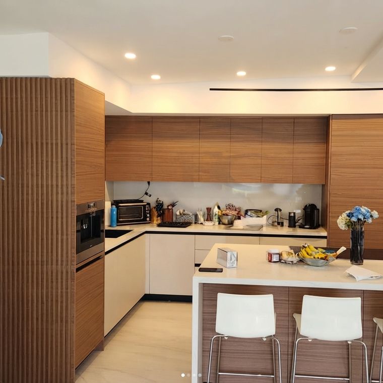 Cocina con panel de listones de madera, barra de desayuno y sillas blancas